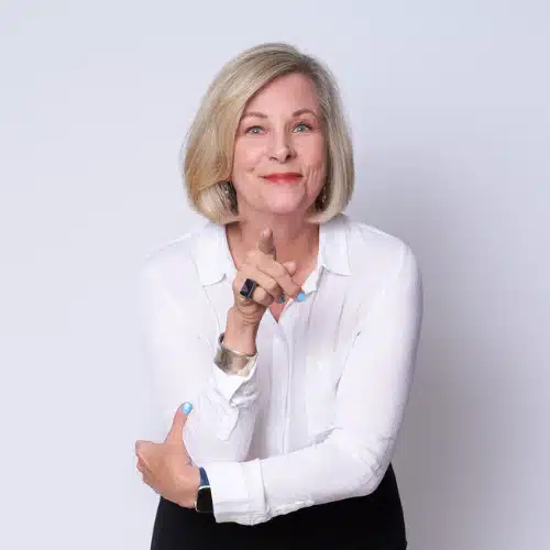 Image of Diann Wingert, ADHD coach, wearing a white top and pointing at the camera, a slight smile on her face.